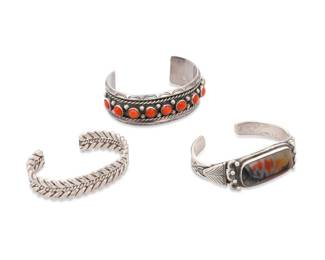 266
Three Southwest style silver and set stone cuff bracelets
Mid/late 20th century
Each unmarked
Three works:

A chunky sterling silver cuff with row set round coral cabochons, silver ball accents and stamped edges
7" total inner C x 1" H, with a 1.625" gap

A narrow tapered silver cuff with central large set petrified wood cabochon, stamp work, and applied silver accents to shoulders
6.75" total inner C x 0.875" H, with a 1" gap

A narrow twisted silver wire cuff with stamped accents
6.125" total inner C x 0.5" H, with a 1" gap

3 pieces
158.2 grams gross
Estimate: $600 - $800