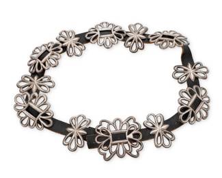 86
A Navajo cast sterling silver concho belt
Early/mid-20th century, Diné
Unmarked
Comprising a chunky filigree openwork buckle with five oval conchos and six narrow filigree spacers, each with copper backings, all mounted to a black leather belt strap
Buckle: 3.25" H x 3.75" W; Each concho: 3.25" H x 3.875" W; Each spacer: 3.125" H x 1.75" W; Belt: 40" L x 1" H
611.3 grams gross
Estimate: $800 - $1,200