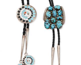 261
Two Southwest sterling silver and set stone bolo ties
Late 20th century
Two works:

Quintus & Denise Peynetsa (each b. 20th century, Zuni)
A Zuni Pueblo Sunface sterling silver and stone inlay bolo tie
With etched signature verso: Quintus & Denise Peynetsa
A round bolo with turquoise, coral and mother of pearl inlay, on a braided leather cord with silver tips and matching round dangles
Bolo: 1.75" Dia.; each dangle: 1" Dia.; cord: 38" L

Tony Guerro (d. 1993, Diné)
A Navajo sterling silver and cluster-set turquoise bolo tie
Stamped verso: Tony Guerro / Sterling
A chunky bolo with ten set turquoise cabochons of various sizes, with incisd edges and silver dot accents, on a braided leather cord with silver tips
Bolo: 2.25" H; cord: 37" L

2 pieces
85.4 grams gross
Estimate: $200 - $400