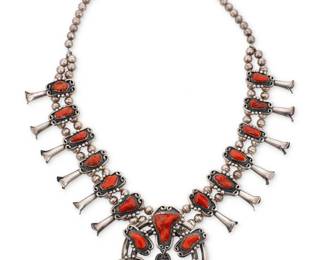 166
A Southwest sterling silver and coral squash blossom necklace
Mid/late 20th century
Unmarked
A chunky double strand sterling silver squash blossom necklace with twelve elaborate set coral 'blossoms' suspending a large two-wire naja with set coral and a central dangle, all with silver ball and wire overlay accents
26.5" L x 3.5" H
301.6 grams gross
Estimate: $800 - $1,200