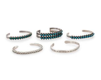 200
A group of Southwest silver and turquoise cuff bracelets
Mid/late 20th century
Four marked for sterling; one marked: RD [possibly Robert K. Deutsawe Jr. Laguna/Zuni Pueblo]; one marked with sunburst picto [possibly Robert Gene, Navajo/Diné]
Five works comprising a two-wire row-set turquoise petit point cuff, a matching single-wire row set turquoise cuff, and a similar style narrow cuff with square set green stones, as well as an RD chunky silver wire cuff with overall zigzag stamp work, and a narrow stamped silver cuff with rounded terminals
5 pieces
Largest: 6.5" total inner C x 0.375" H, with a 1 3/8" gap; Smallest: 5.75" total inner C x 0.125" H, with a 1" gap
90.5 grams gross
Estimate: $600 - $800