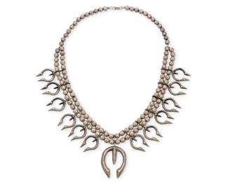 160
A Southwest cast sterling silver squash blossom necklace
Early/mid-20th century
Unmarked
A double strand of large silver beads suspending a central cast silver naja and twelve graduated cast silver blossoms
26.75" L x 2.75" H
210.2 grams
Estimate: $1,000 - $1,500