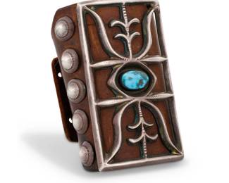 87
A Navajo sandcast sterling silver and turquoise ketoh arm guard
Mid-20th century, Diné
Unmarked
A large cast silver openwork rectangular medallion with set central turquoise cabochon, attached to a shaped leather arm band and further set with five stamped silver pointed rivets
Silver: 4" H x 2.25" W; Band: 4" H x 9.25" W
141.4 grams gross
Estimate: $600 - $800