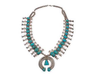 164
A Southwest 'Box and Bow' silver and turquoise squash blossom necklace
Early/mid-20th century
Unmarked
With a central stone-set sterling silver two-wire naja and twenty-four graduated box and bow stamped sterling silver blossoms, all set to a double-strand of silver beads
26.5" L x 2.75" H
261.6 grams gross
Estimate: $1,000 - $2,000