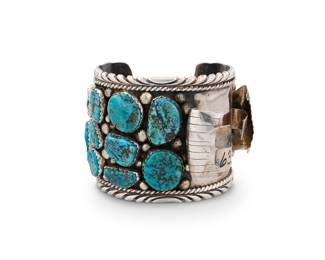 193
A Southwest sterling silver and turquoise watch cuff
Mid/late 20th century
Unmarked
A Navajo-style chunky cuff with multiple set turquoise stones and silver ball accents, with off-set watch mounting
7" total inner C x 2.5" H, with a 1.25" gap
164.5 grams gross
Estimate: $500 - $700