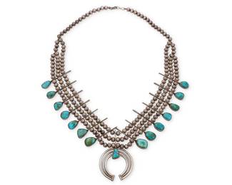 163
A Southwest sterling silver and turquoise squash blossom necklace
Early/mid-20th century
Unmarked
With a triple strand of silver pearls suspending fourteen turquoise cabochon 'blossoms' suspending a three-wire and set turquoise naja
26" L x 3.25" H
158.8 grams gross
Estimate: $1,000 - $1,500