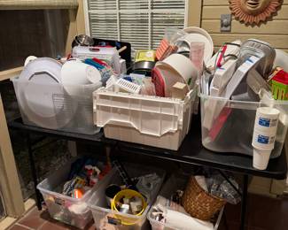 Totes filled with storage containers, paper, plates, napkins, outdoor serving pieces