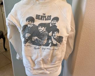 Original vintage sweatshirt featuring The Beatles. Cream-colored with black and white print of the band members and their signatures on the front. Classic crew neck style with raglan sleeves. Shows signs of wear consistent with age, including minor discoloration and staining. Chest width approximately 20 inches. A collectible piece for Beatles fans and vintage clothing enthusiasts.
Please defer to photos for condition. 15% Buyer's Premium. We only ship with USPS Priority Mail Flat Rate Shipping. Items with value over $100 shipping insurance must also be charged to you to protect your purchase. Please contact us regarding shipping in advance if you have any questions.
Alternative pick-up times are very limited. Please consider pick-up hours when bidding. Items that are not picked-up and shipping arrangements have not been made/paid for within 7 days will be considered abandoned.