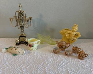 Charming assorted vintage decorative objects collection featuring a polished brass candelabra, a miniature ceramic tea set, a yellow glass shoe figurine, and several additional novelty and figural décor pieces.