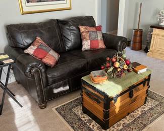 Faux leather loveseat, antique trunk, area rug, barrel butter churn (sun's glare on photo)