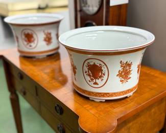 Elegant pair of Mottahedeh porcelain cachepots, beautifully decorated with classical urn and floral motifs in warm rust tones. Known for producing high-quality reproductions of historic European and Chinese export porcelain, Mottahedeh pieces are prized for their craftsmanship and timeless design. Perfect as planters, centerpieces, or decorative accents. A sophisticated addition to any traditional or collected interior. Pair offered together.