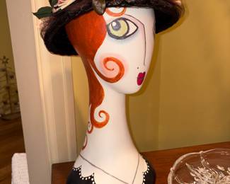 Brightly featured Lady holding hat with flowers 