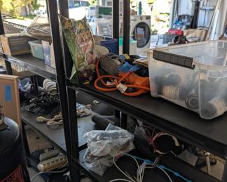 Garage Shelving & Supplies: Heavy-duty black plastic garage shelving loaded with extension cords, work lights, hardware bins, and yard supplies.