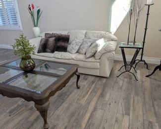 Living Room Setup: Wide room view featuring our pristine white leather sofa, dark wood glass-top coffee table, and the beautiful mosaic/wrought-iron side table.