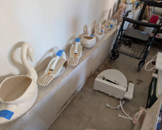Vintage Ceramic Swans: A beautiful collection of elegant white ceramic swan planters and decorative bowls in various sizes, some featuring delicate gold-painted accents on their wings and beaks.

Rolling Walker with Seat: A heavy-duty, four-wheel mobility walker (rollator) equipped with handbrakes, a padded resting seat, and a backrest.

Toto Washlet Bidet: A clean, white Toto electronic washlet/bidet toilet seat complete with the attached side control panel for heating and washing functions.