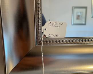 P12 - $30. Pair of Silver Framed Mirrors. Measures 21" wide x 25" tall.