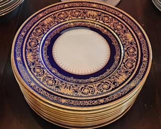 Elegant Set of (12) Early 20th Century Minton, Stoke-on-Trent, Cobalt Blue Medallion Dinner Plates. Each plate measuring 10 inches in diameter with a scalloped edge, adorned with an intricate pattern of gilt vines and acanthus leaves throughout.