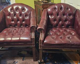 Pair of English Chesterfield tufted leather club chairs, featuring burgundy leather, brass nail head trim and casters.