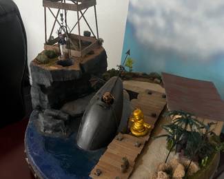 Handcrafted Rotating Diorama Sculpture “Submariner Depot and Beach Bar”   – By Grady Keeton  Unique, one-of-a-kind hand-built diorama sculpture from a private estate. This detailed nautical scene features a surfaced submarine, dock, tower, shoreline, and miniature figures, all mounted on a custom riveted circular base that rotates for full 360° display. Signed and titled by the artist. A striking conversation piece for collectors of folk art, maritime décor, or narrative sculpture. Valued at $750.00 Asking price only $175.00