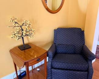 Blue upholstered armchair with side table and oval wall mirror