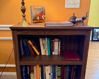 Dark wood bookshelf with books, brass table lamp, decor