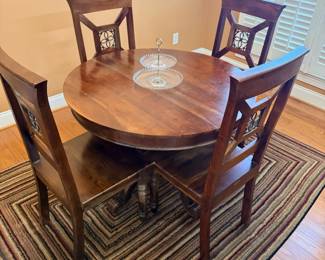 Round pedestal dining table with decorative back chairs, side view
