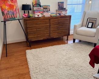 Living room with white shag rug, wood dresser, framed art, armchair