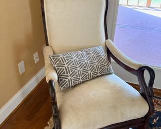 Cream upholstered armchair with wood frame and throw pillow