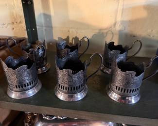 vintage metal holders are known as Podstakanniks (tea glass holders), historically used in Russian tea culture to safely hold hot drinking glasses. 