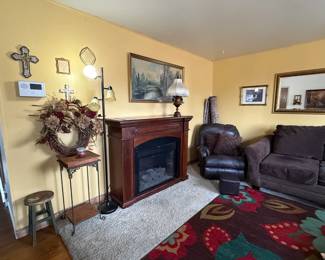 Electric fireplace; couch; area rugs; gold ornate framed mirror and prints; home decor; lamps