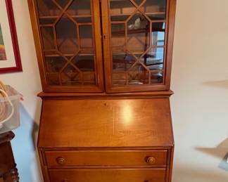 vintage secretary desk, featuring a top hutch with glass doors and a drop-front writing surface over drawers.
: