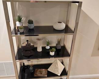 Modern chrome frame shelving unit with 5 black glass shelves. Sleek, contemporary design. Great for displaying decor, books, or plants in a living room, office, or bedroom. Sturdy and in excellent condition.( Items on Shelf not included for sale seperatly)