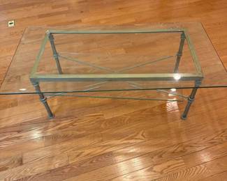 Glass coffee table with solid metal frame and two-tier design. Clean, classic look and very sturdy. Details: • Size: 50” L x 25” W x 18” H • Heavy glass top and lower shelf • No cracks or chips • Normal cosmetic wear on frame (see photos)