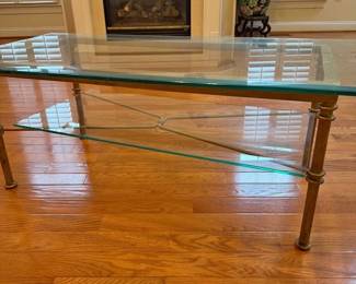 Glass coffee table with solid metal frame and two-tier design. Clean, classic look and very sturdy. Details: • Size: 50” L x 25” W x 18” H • Heavy glass top and lower shelf • No cracks or chips • Normal cosmetic wear on frame (see photos)