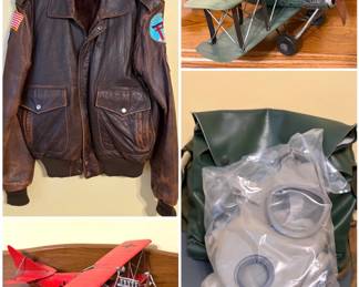 A vintage brown leather Type A-2 bomber jacket by the brand Avirex, a decorative metal model of a World War I German biplane, a metal model of a vintage WWI British biplane, and a vintage military gas mask. 