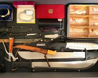 a collection of knives, including fixed-blade knives, machetes, and folders. 
