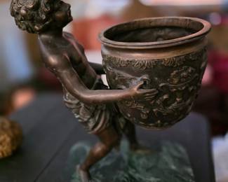 This vintage sculpture appears to be a late 19th-century French patinated bronzed spelter figure of a young boy carrying a water jug, typically attributed to the artist Auguste Moreau. 