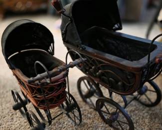 These are vintage, collectible doll strollers, often designed in a Victorian wicker and iron style. 