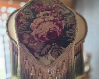 Victorian-style lampshade featuring burgundy roses on a gold shot silk damask fabric, adorned with a glass bead ombré fringe. 