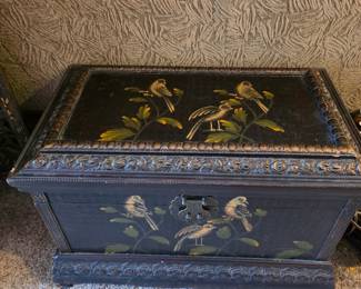 This item appears to be a vintage or antique decorated wooden chest, likely in the chinoiserie style. 
It features a black lacquered finish with detailed hand-painted bird and foliage motifs on both the lid and the front. 