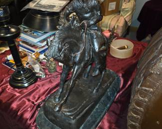 This item is a bronze sculpture titled "The Bronco Buster" by Frederic Remington, portraying a cowboy struggling to control a rearing horse. 