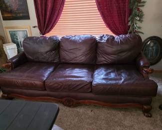 This is a traditional-style, deep maroon-colored leather sofa featuring a wooden base and decorative carving. 