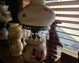  Victorian-style hurricane lamp, often referred to as a "Gone With the Wind" lamp. 
It features hand-painted pink rose designs on both the scalloped glass shade and the milk glass base.