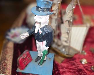 This item is a vintage cast iron Uncle Sam mechanical coin bank. 
Material: Cast iron.
Design: Features Uncle Sam, the national personification of the U.S. government, often hand-painted.