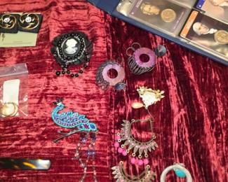 
Avon Peacock Brooch: A colorful, rhinestone-embellished brooch shaped like a peacock, featuring dangling elements.
Costume Jewelry: Various other brooches, clip-on earrings, and rings featuring rhinestone, filigree, and cameo designs.