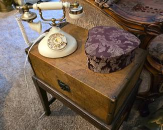 vintage-style rotary telephone on top of a classic storage side table, which is likely a collectible or antique sewing cabinet. 