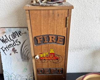 “Rustic ‘Fire Dept.’ wall cabinet with decorative vintage fire engine detail. Includes fire extinguisher. Great for farmhouse, garage, or workshop décor.