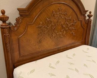 Ornate wooden bed with footboard and mattress 