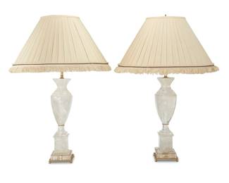 344 Two Neoclassical style rock crystal table lamps Late 20th century Each with vasiform body above an architectural base, issuing two lights and surmounted by a pleated fabric shade with fringe, electrified 2 pieces Each lamp: 32" H x 4.75" Dia.; Each shade: 11" H x 20.5" Dia. Estimate: $1,000 - $1,500