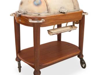 322 A Maison Renaud & J Clermont Art Deco meat serving trolley 1930s With applied metal label: Renaud & J Clermont S. A. / Genève / Fournitures Générales Pour Hótels The silver-plated and mahogany hot meat carving trolley with retractable dome opening to reveal a removeable bain-marie heated by an alcohol burner, the carving platform with au jus well and two removeable sauce compartments, with handles at corners, a folding wine bottle surface, a hanging tray for serving utensils, and an undertier, all raised on columnar supports with rubber casters With dome shut: 43.5" H x 39" W x 25" D; Retracted: 39" H Estimate: $500 - $700